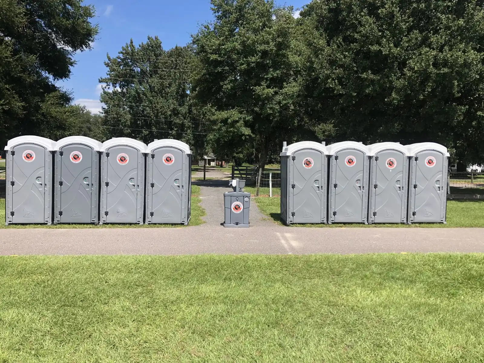 Two groups of four Bingham On-Site portable toilets with a hand-wash station between them on grass